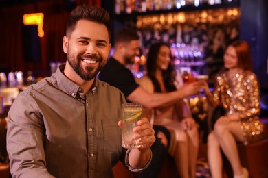 Photo of Friends spending time together in bar. Handsome man with fresh alcoholic cocktail, space for text