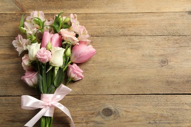 Photo of Happy Mother's Day. Bouquet of beautiful flowers tied with pink ribbon on wooden table, top view. Space for text