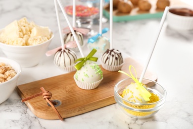 Tasty colorful cake pops on white marble table