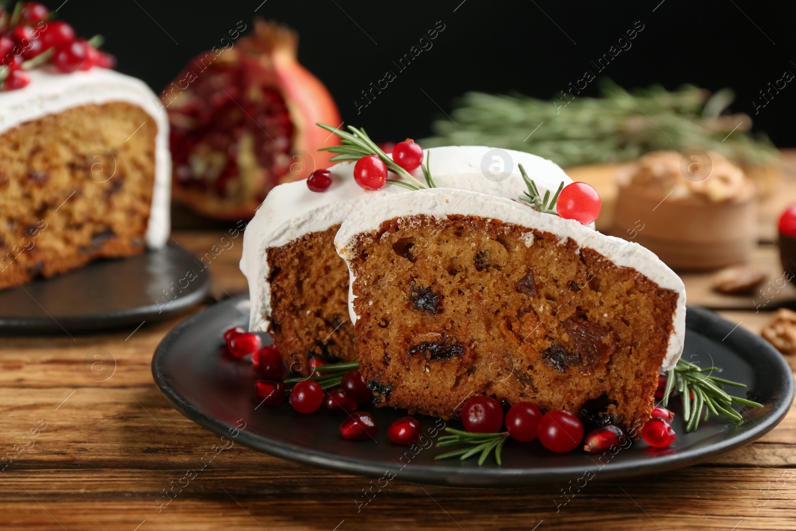 Photo of Traditional classic Christmas cake decorated with cranberries, pomegranate seeds and rosemary on wooden table