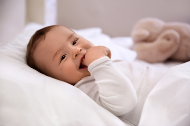 Photo of Cute little baby lying in comfortable crib. Bedtime