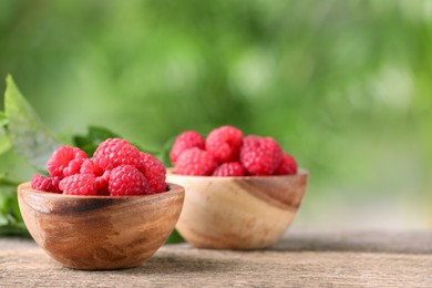 Photo of Tasty ripe raspberries in bowl on wooden table outdoors. Space for text