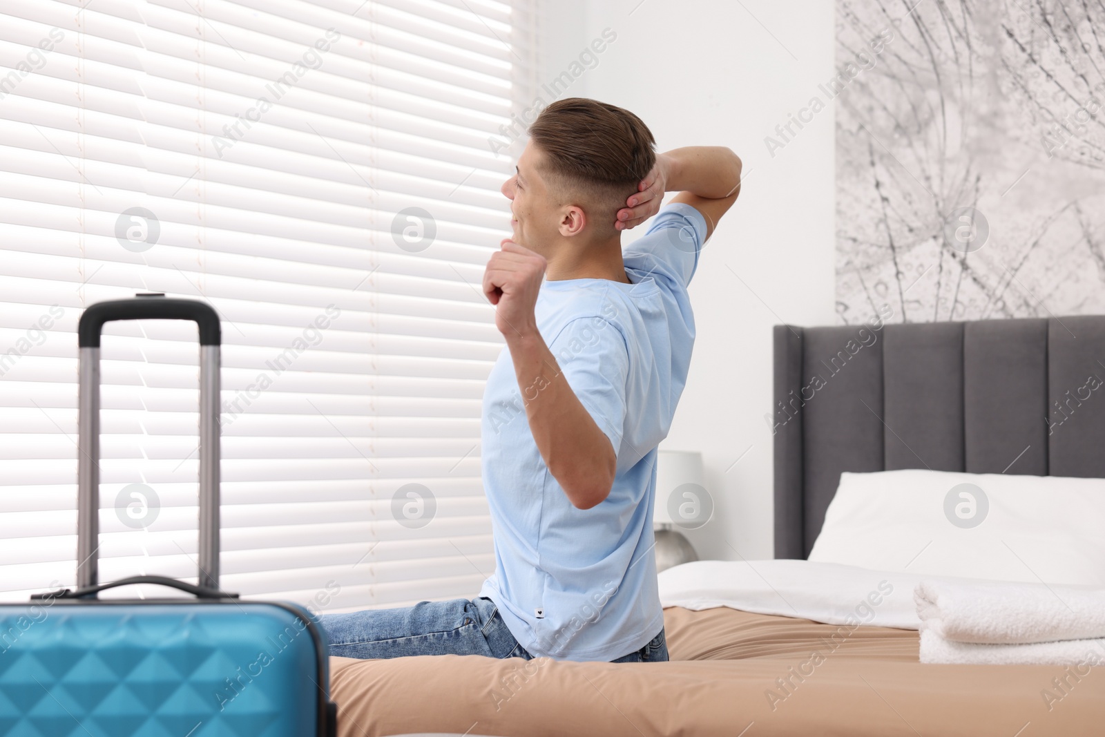 Photo of Guest stretching on bed in stylish hotel room