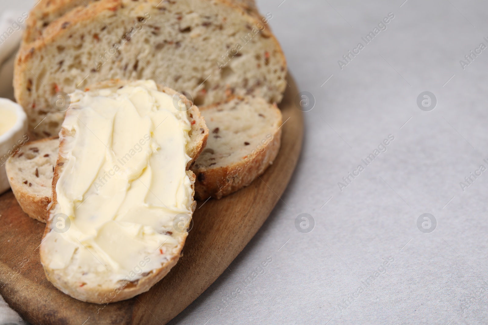 Photo of Tasty bread with butter on gray table, closeup. Space for text