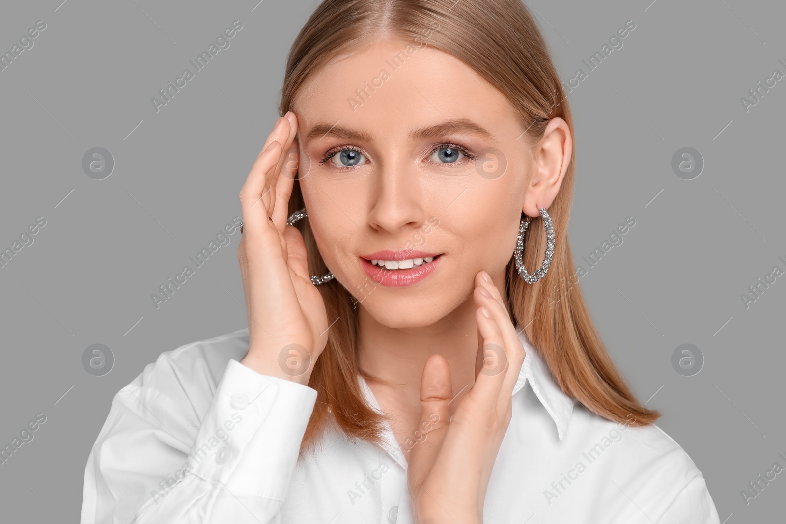 Photo of Beautiful young woman with elegant earrings on gray background