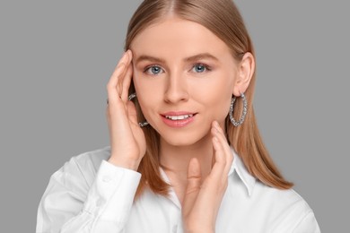 Photo of Beautiful young woman with elegant earrings on gray background