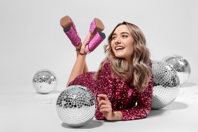 Photo of Beautiful woman in pink dress among disco balls on white background