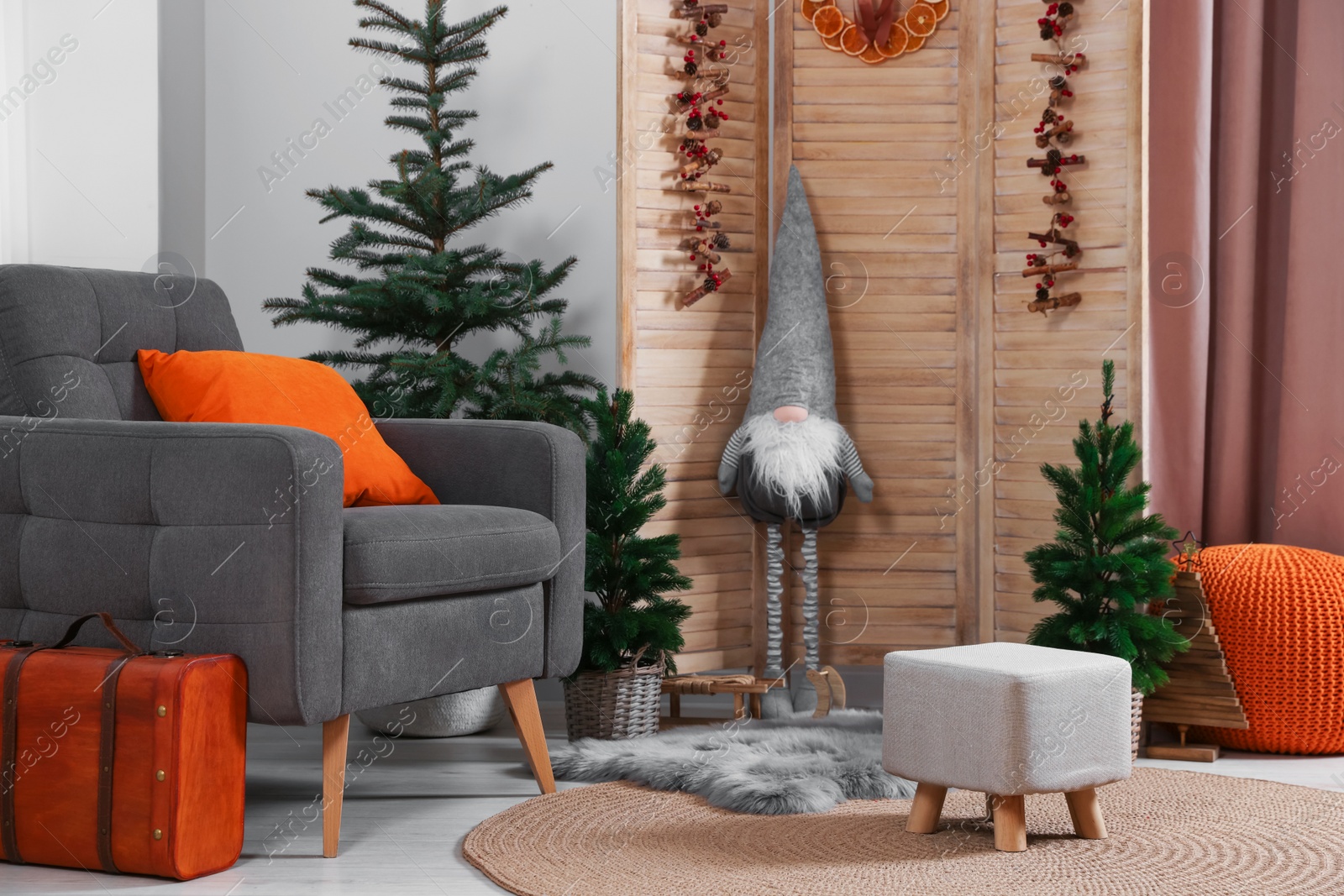 Photo of Beautiful Christmas themed photo zone with trees, dwarf and armchair in room