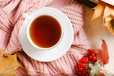 Flat lay composition with cup of aromatic tea and soft pink sweater on beige textured table. Autumn atmosphere