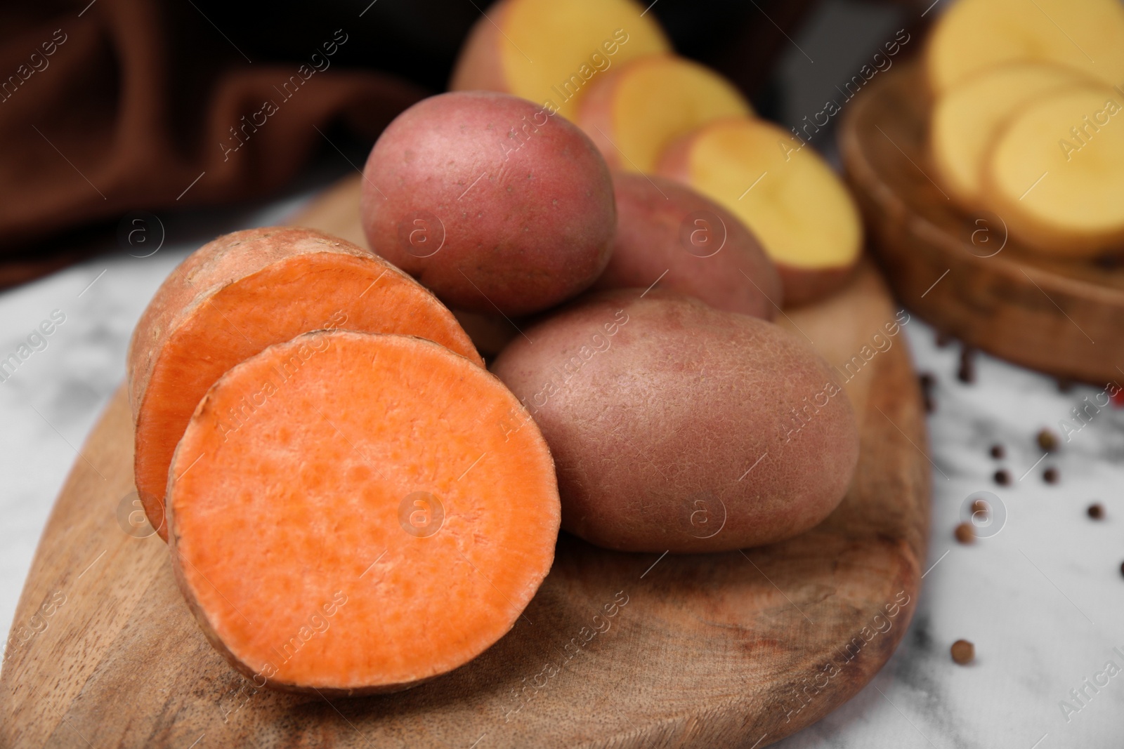 Photo of Different types of fresh potatoes on wooden board, closeup