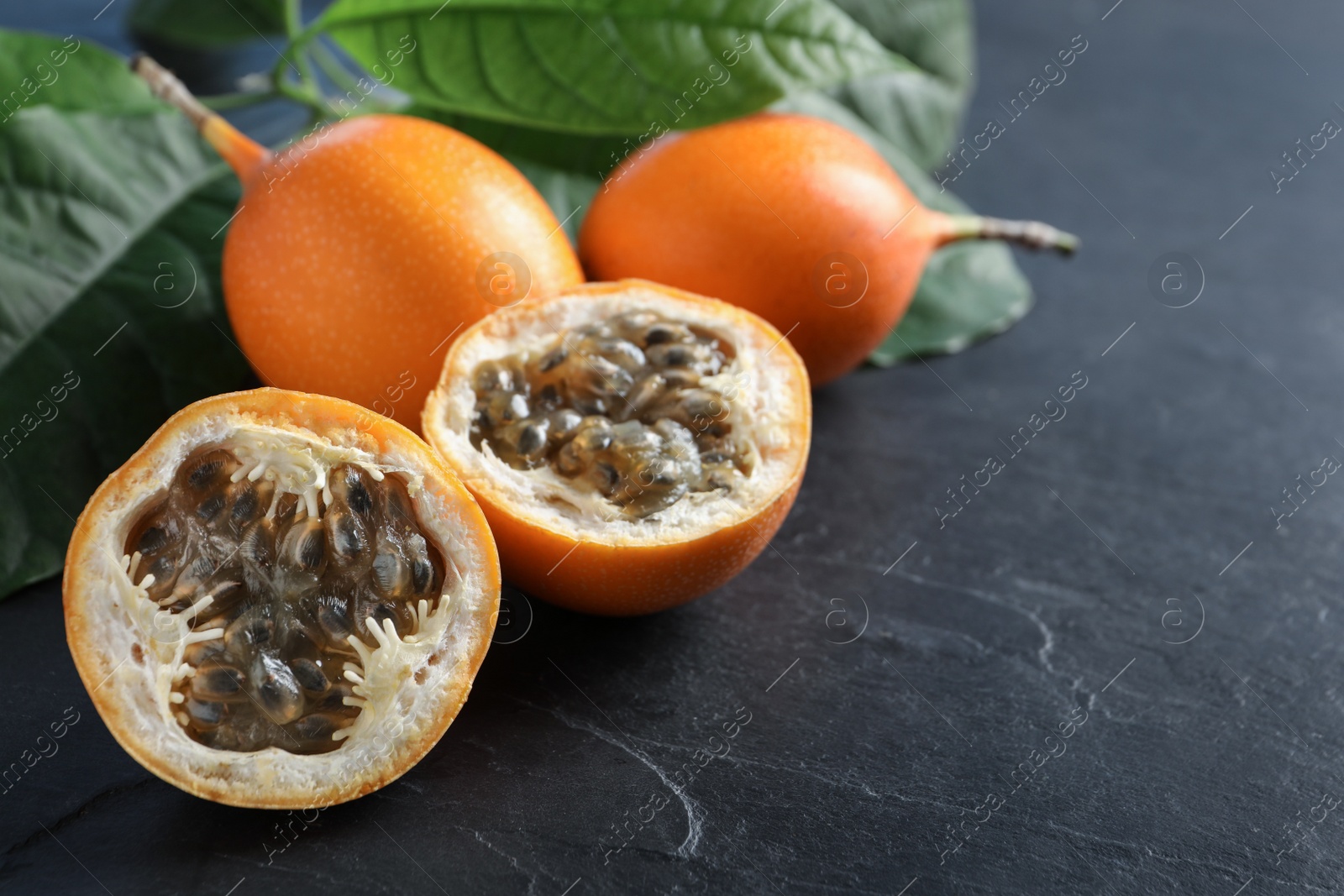 Photo of Delicious fresh ripe granadillas on black table