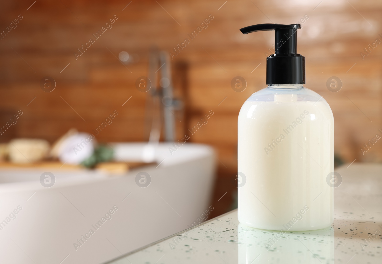 Photo of Dispenser of liquid soap on white table in bathroom, space for text