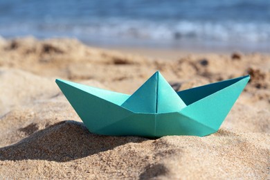 Photo of Green paper boat near sea on sunny day, closeup