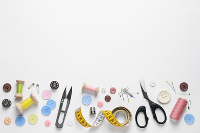 Flat lay composition with scissors and sewing supplies on white background. Space for text