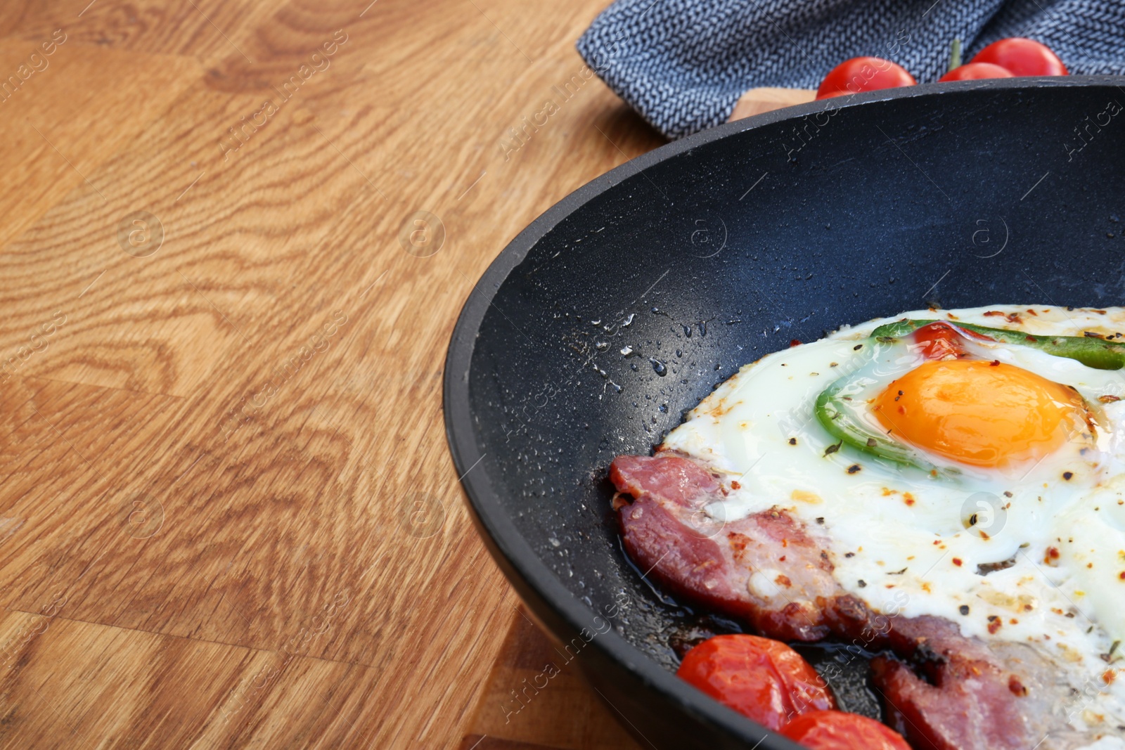 Photo of Delicious fried egg with bacon, tomatoes and pepper served on wooden table, closeup. Space for text