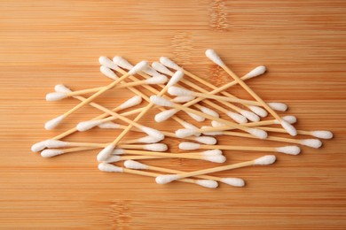 Photo of Heap of clean cotton buds on wooden table, flat lay