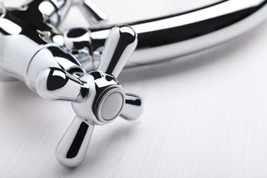 Photo of Double handle water tap on white wooden table, closeup