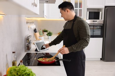 Man using tablet while cooking in kitchen
