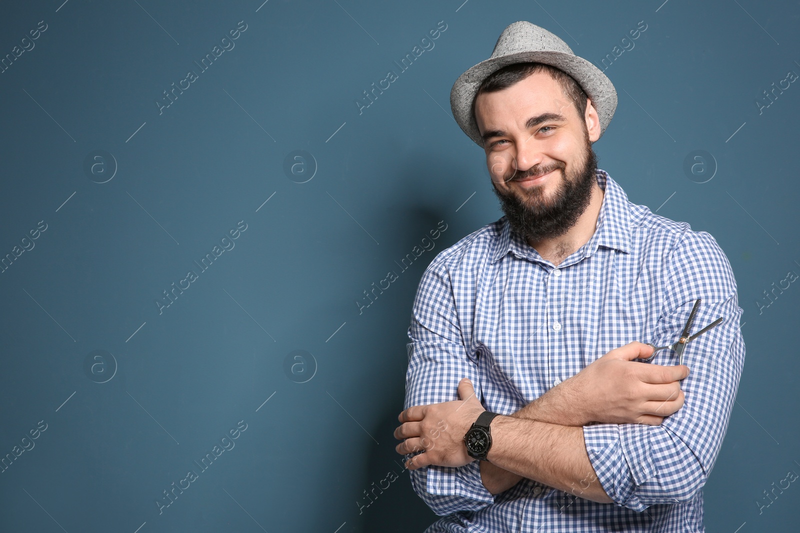 Photo of Professional hairdresser with scissors on color background