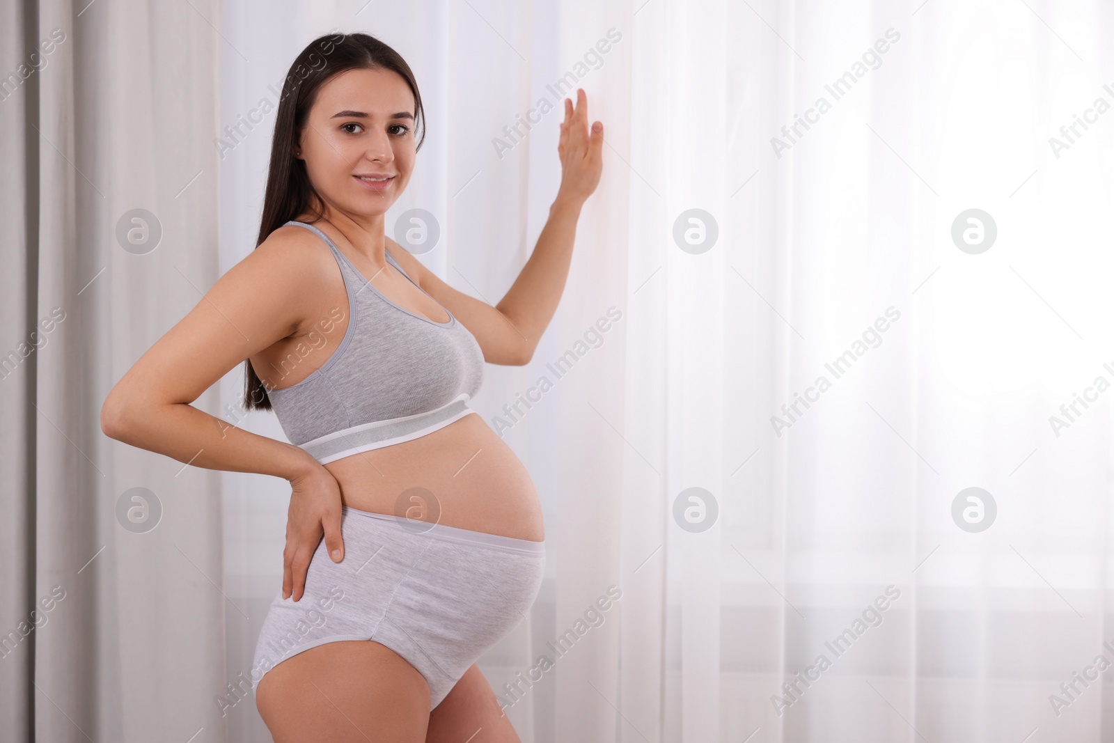 Photo of Beautiful pregnant woman in comfortable maternity underwear indoors, space for text