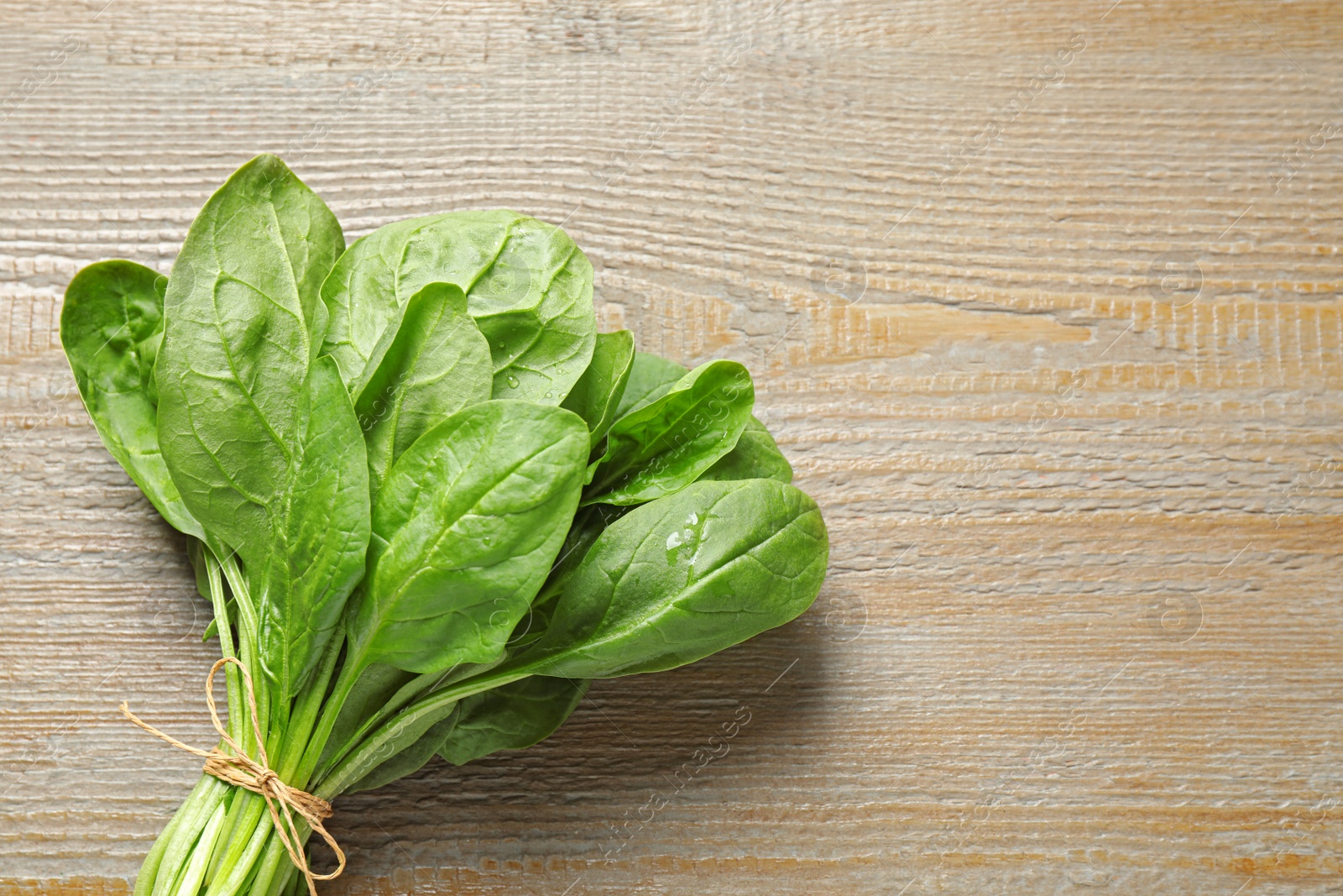 Photo of Bunch of fresh green healthy spinach on wooden table, top view. Space for text