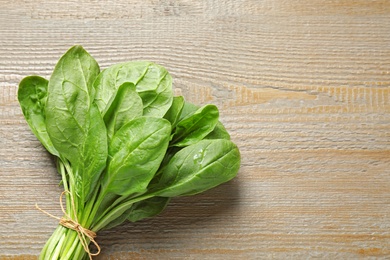 Photo of Bunch of fresh green healthy spinach on wooden table, top view. Space for text