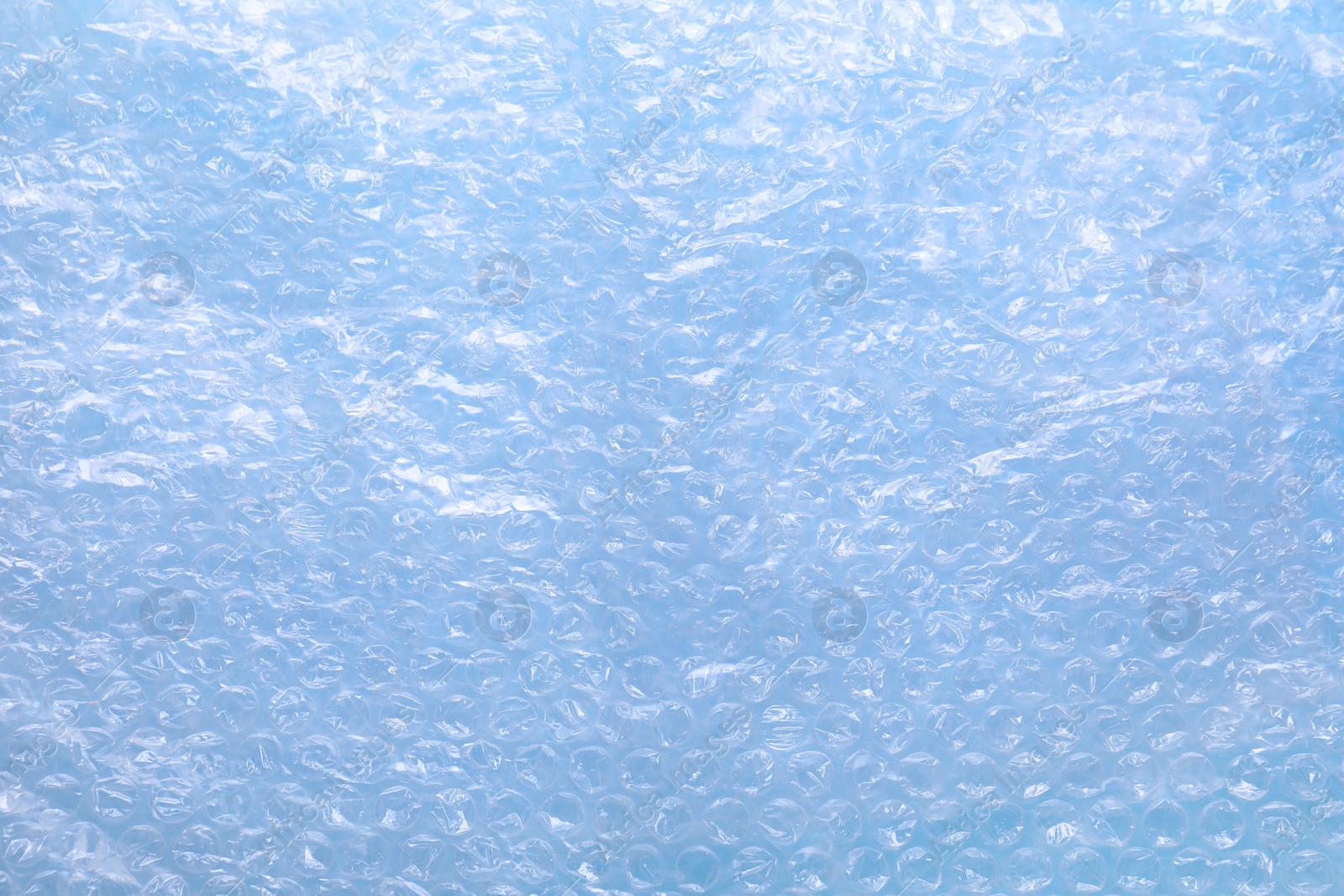 Photo of Transparent bubble wrap on light blue background, top view