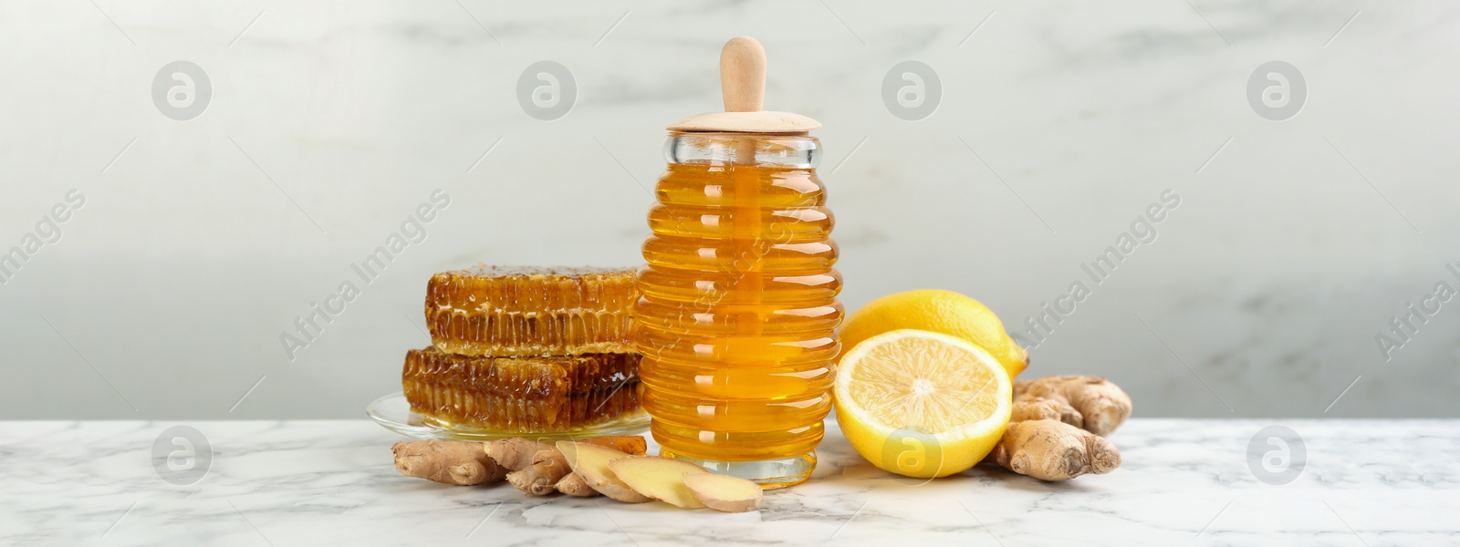 Image of Tasty aromatic honey, lemon and ginger on white marble table. Banner design