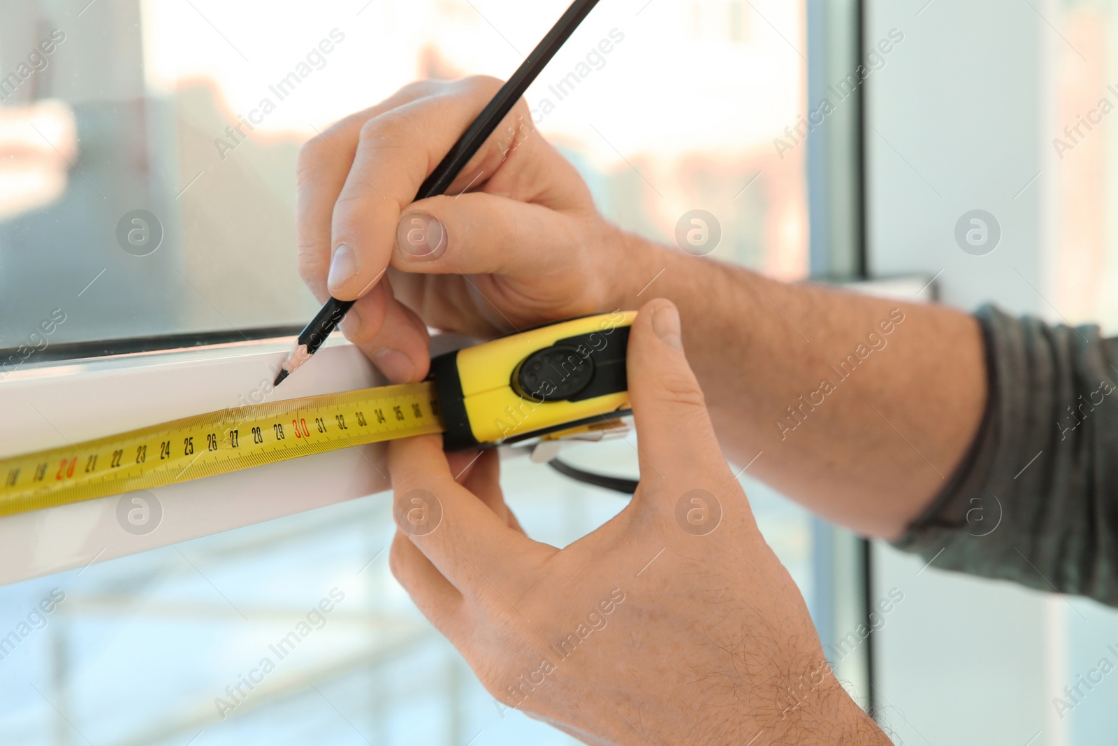 Photo of Service man measuring window for installation indoors, closeup