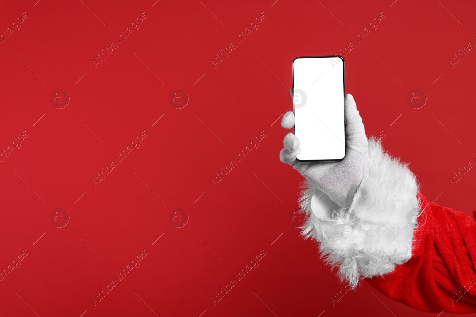 Photo of Merry Christmas. Santa Claus showing smartphone on red background, closeup. Mockup for design