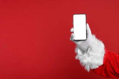 Photo of Merry Christmas. Santa Claus showing smartphone on red background, closeup. Mockup for design