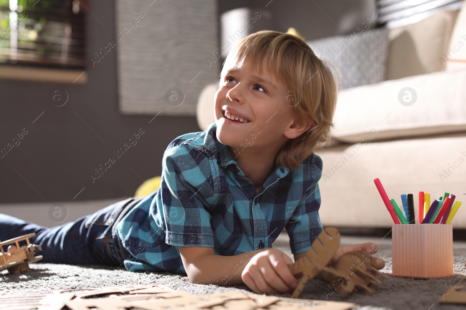 Photo of Little boy making cardboard toys on floor at home. Creative hobby