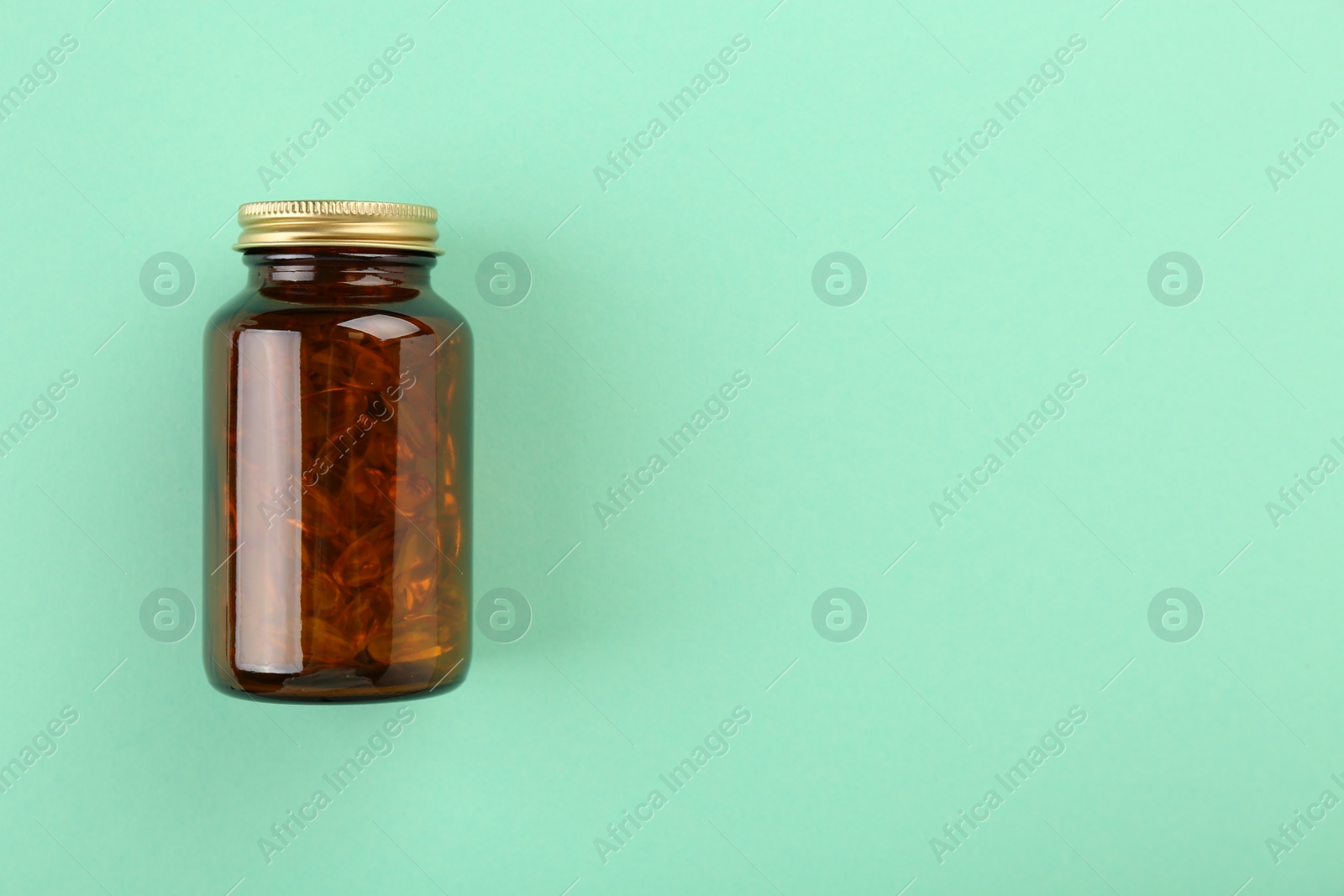 Photo of Bottle with vitamin capsules on turquoise background, top view. Space for text