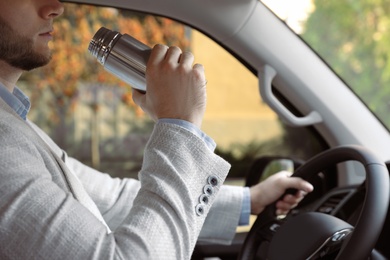 Photo of Man with thermos driving car, closeup view