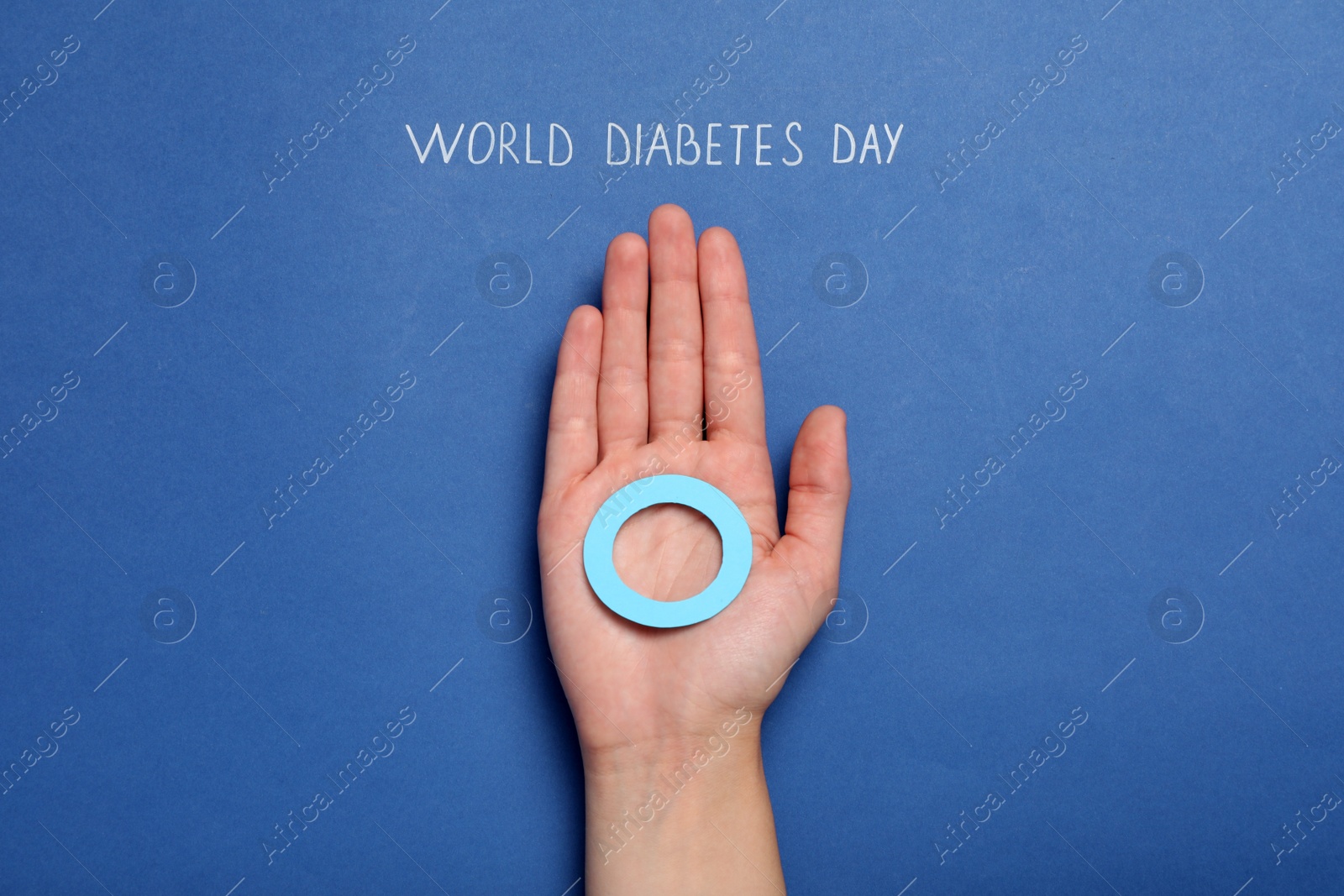 Photo of Woman holding blue paper circle near text World Diabetes Day on color background, top view