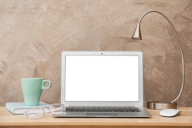 Photo of Laptop on desk against color wall in home office. Comfortable workplace