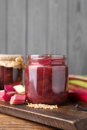 Tasty rhubarb sauce and ingredients on wooden table, space for text