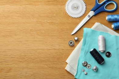 Photo of Flat lay composition with spools of threads and sewing tools on wooden table. Space for text