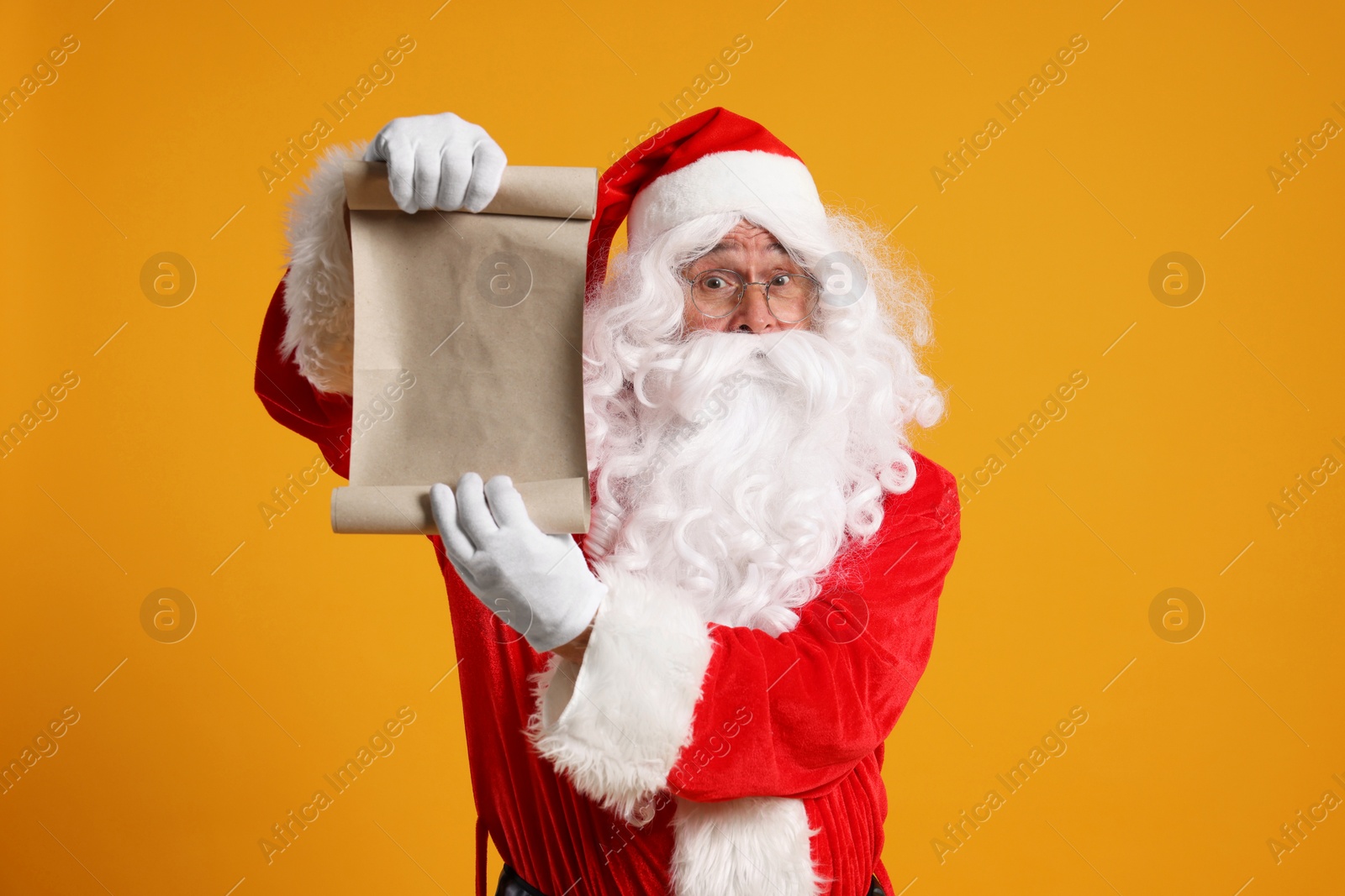 Photo of Merry Christmas. Santa Claus showing blank paper sheet on orange background