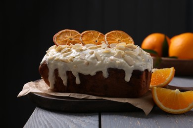 Delicious sweet cake with dry orange and almond petals on grey wooden table