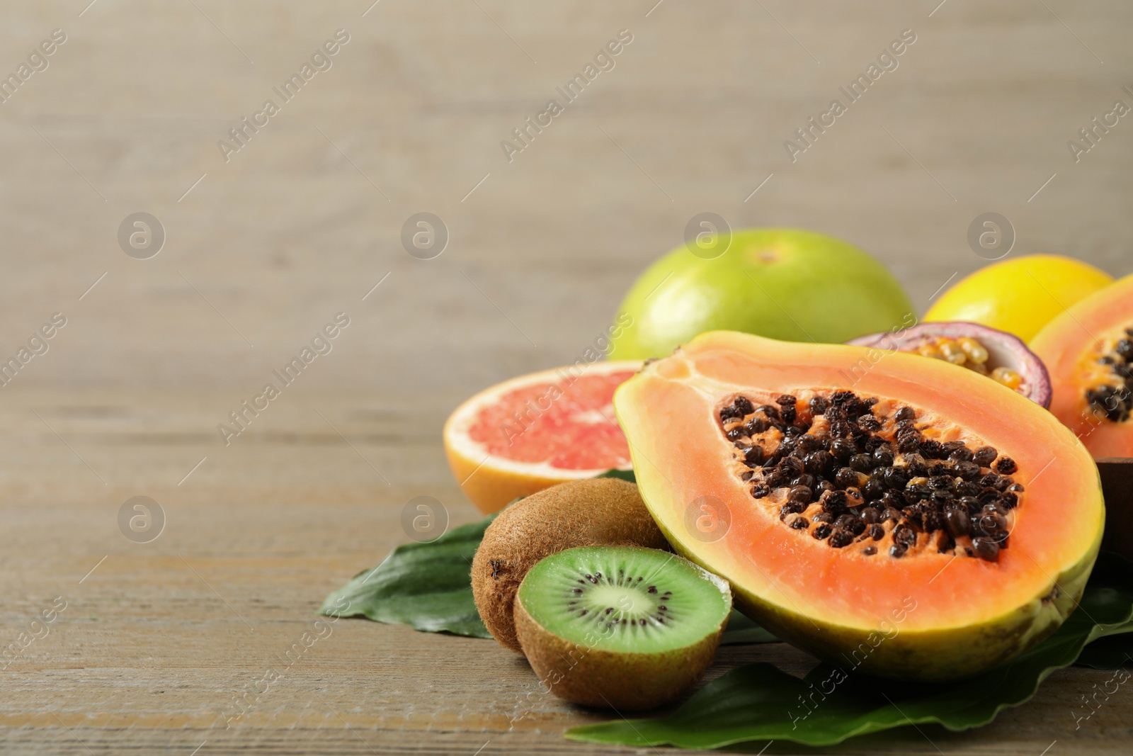 Photo of Fresh ripe papaya and other fruits on wooden table. Space for text