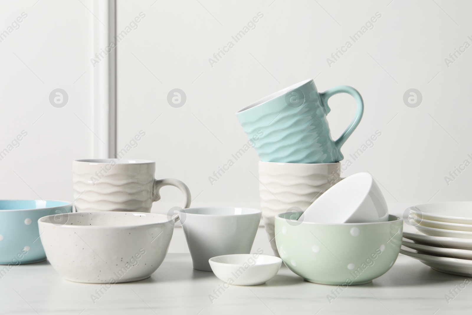 Photo of Beautiful ceramic dishware and cups on white marble table