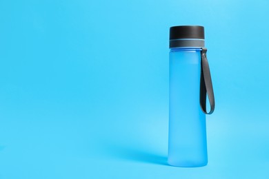 Photo of Stylish bottle on light blue background, space for text