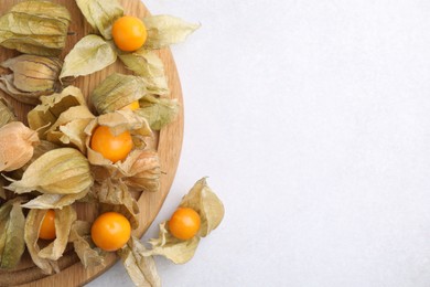 Photo of Ripe physalis fruits with calyxes on white table, top view. Space for text