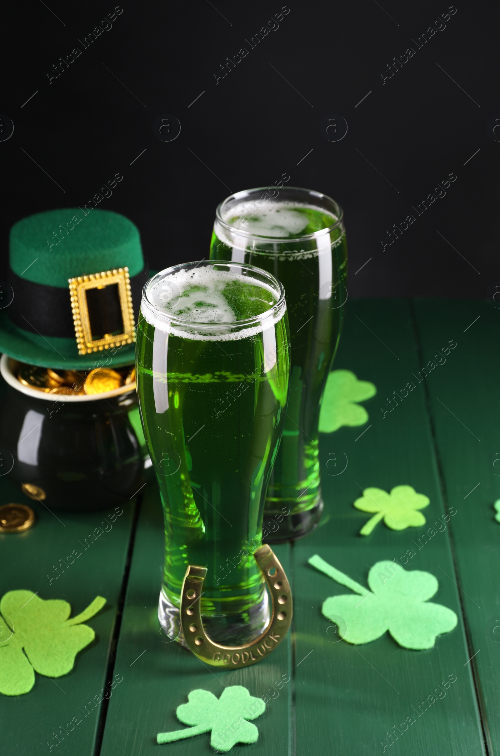 Photo of St. Patrick's day party. Green beer, leprechaun hat, pot of gold, horseshoe and decorative clover leaves on wooden table