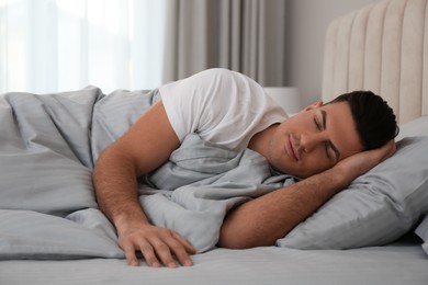 Photo of Man sleeping in bed with grey linens at home
