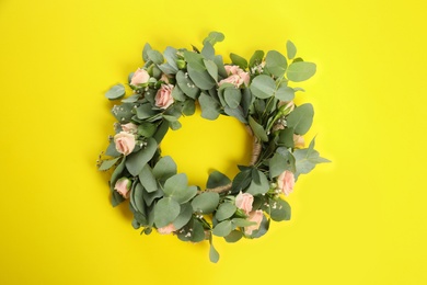 Photo of Wreath made of beautiful flowers on yellow background, top view
