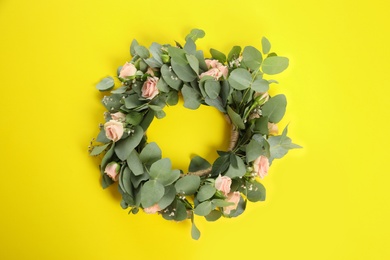 Wreath made of beautiful flowers on yellow background, top view