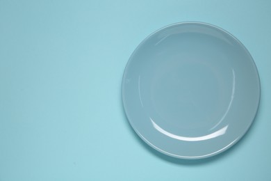 Photo of One ceramic plate on light blue background, top view. Space for text