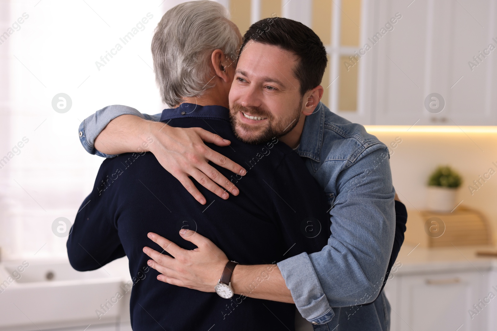 Photo of Happy son and his dad hugging at home